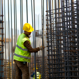 Trabajador con casco amarrando varillas de acero
