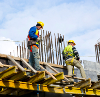 Trabajadores con casco sobre una estructura en altura, trabajo en alturas